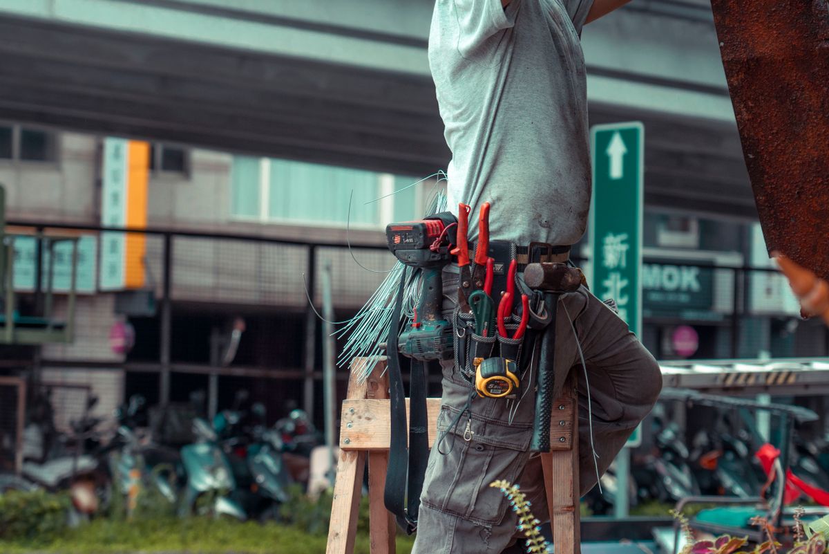 Handyman en una escalera con cinturón de herramientas