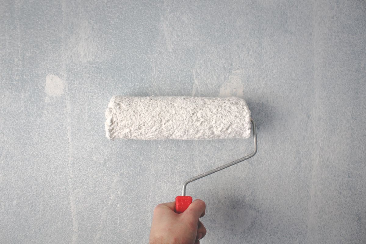 Rodillo aplicando pintura blanca en una pared